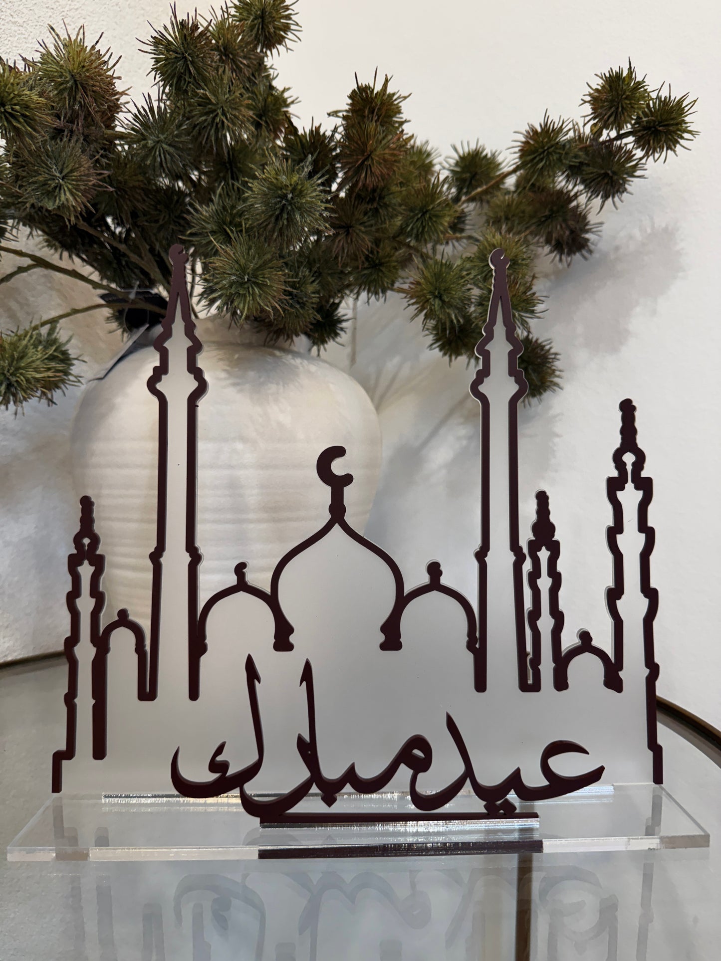 Decorative metal art piece with Islamic architectural elements and Arabic text, placed against a neutral background.
