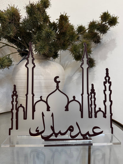 Decorative metal art piece with Islamic architectural elements and Arabic text, placed against a neutral background.