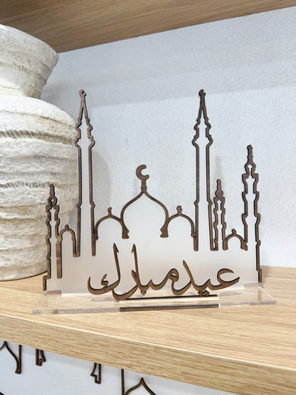Decorative metal art piece with architectural designs on a wooden surface