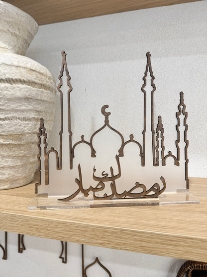 Decorative metal art piece on a shelf with a white wall background